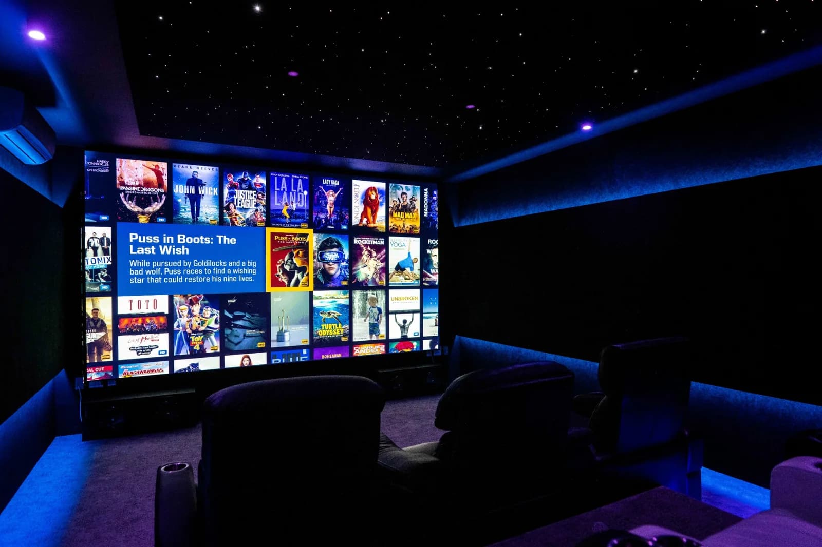 DSG Metro theater with a projection screen, star ceiling, blue cove lighting, and recliners